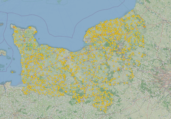 Capture d'écran dans QGIS. Apparait la couche de données Sandre (liste des stations d'épuration à l'échelle nationale). Les installations identifiées en Normandie sont des gros points jaunes, environ un bon millier, globalement dispersés sur toute la région. On voit également des petits points gris. Il s'agit des installations hors périmètres ou déjà traitées/reportées sur OSM.