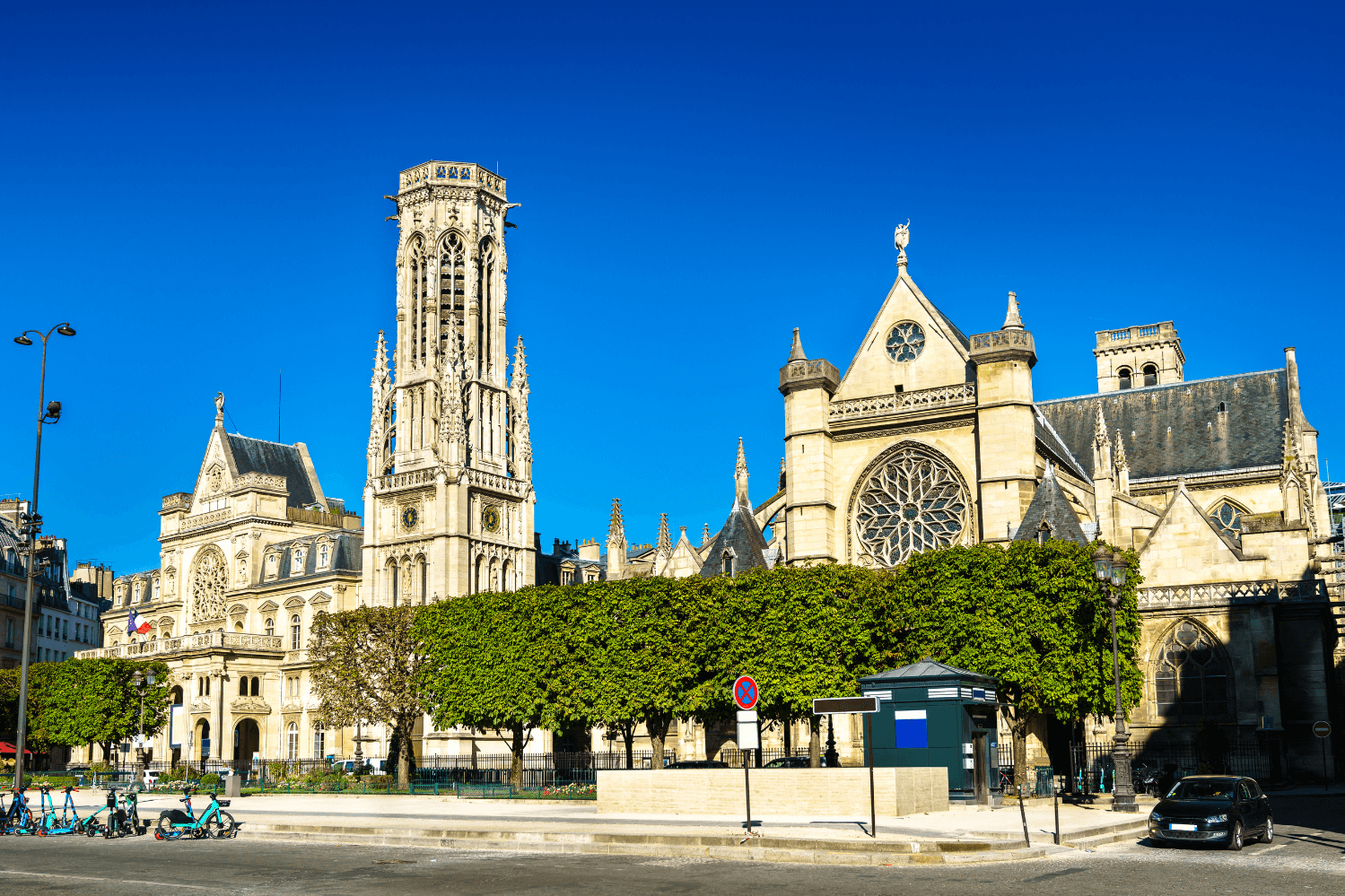 Église Saint-Germain-des-Prés à Paris, un monument historique situé au cœur du quartier Saint-Germain-des-Prés, présentant une magnifique architecture gothique et entourée de verdure sous un ciel bleu éclatant.