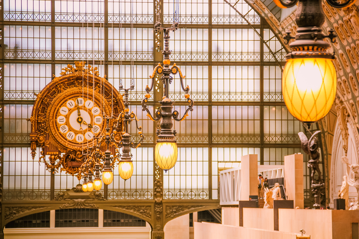 Intérieur du Musée d’Orsay à Paris, mettant en avant l’imposante horloge ornementale et l’éclairage Art déco, avec des sculptures exposées au premier plan.