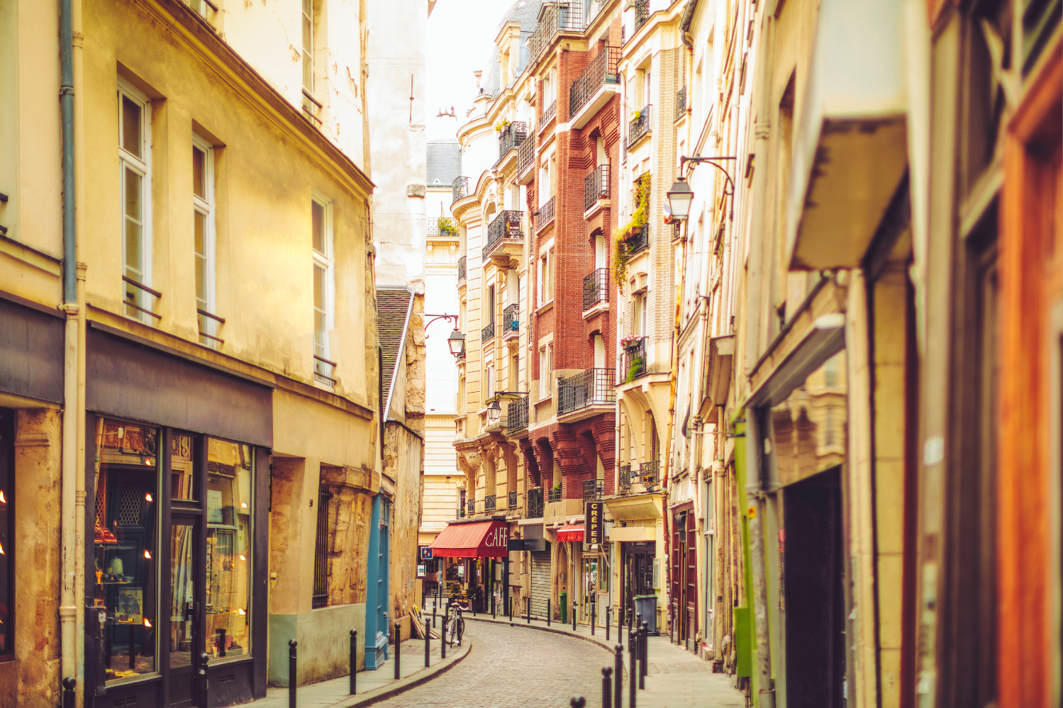 Une rue pittoresque et étroite du Quartier Latin à Paris, bordée de bâtiments historiques, de petites boutiques et d’un café aux auvents rouges, reflétant l’atmosphère vivante et charmante du quartier.