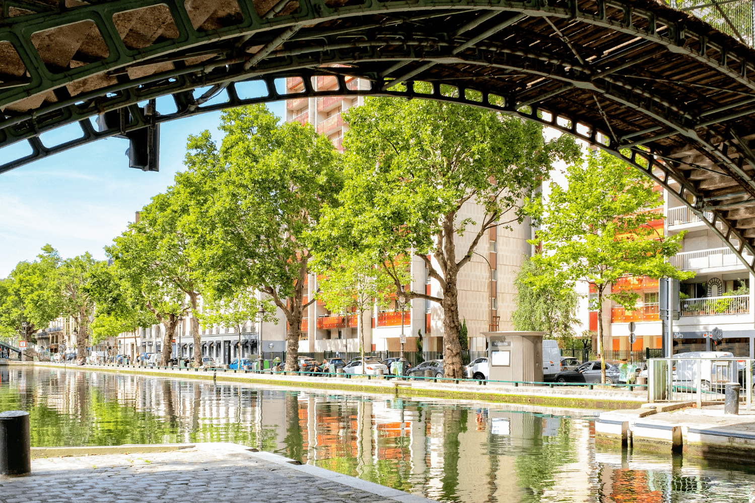 Picturesque view of Canal Saint-Martin in the 10th arrondissement of Paris, framed by an iconic bridge, with tree-lined banks and reflections of Parisian charm, a favorite spot for locals and visitors alike.