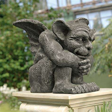 Picture of a gargoyle sitting on his butt, his knees drawn up to his chest, his arms around him, he looks a bit naive, soft, almost childlike